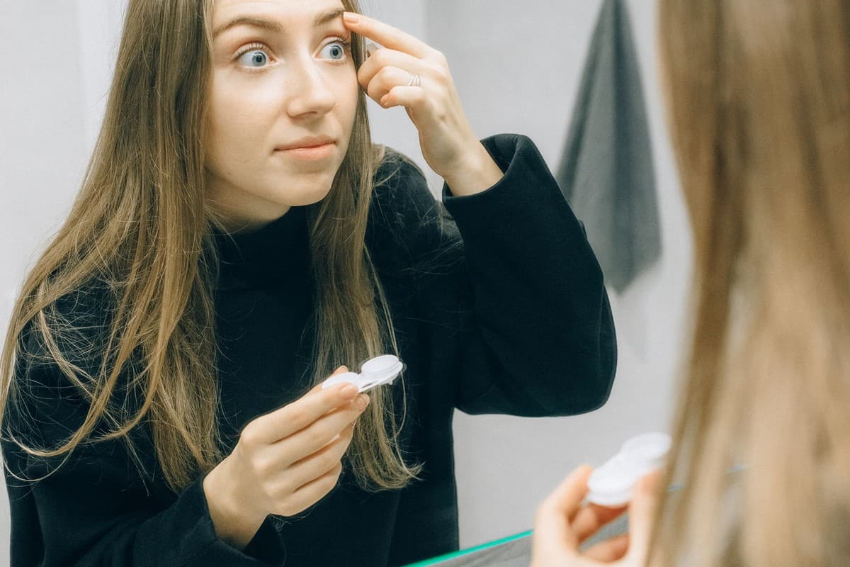 A person using contact lenses in front of a mirror